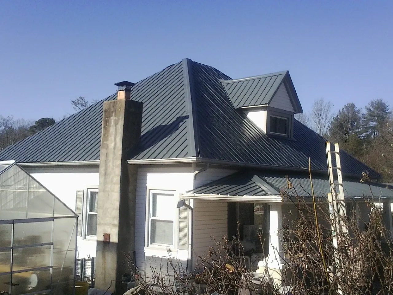 Dark blue standing seam metal roof on a white farmhouse with dormer — Slate & Tile Roof Repair by Roofing Brothers in Gray Court