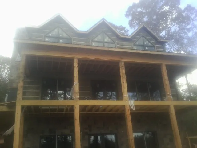 Dormers and porch framing on a large log home under construction — Roof Coating work by our crew in Gray Court