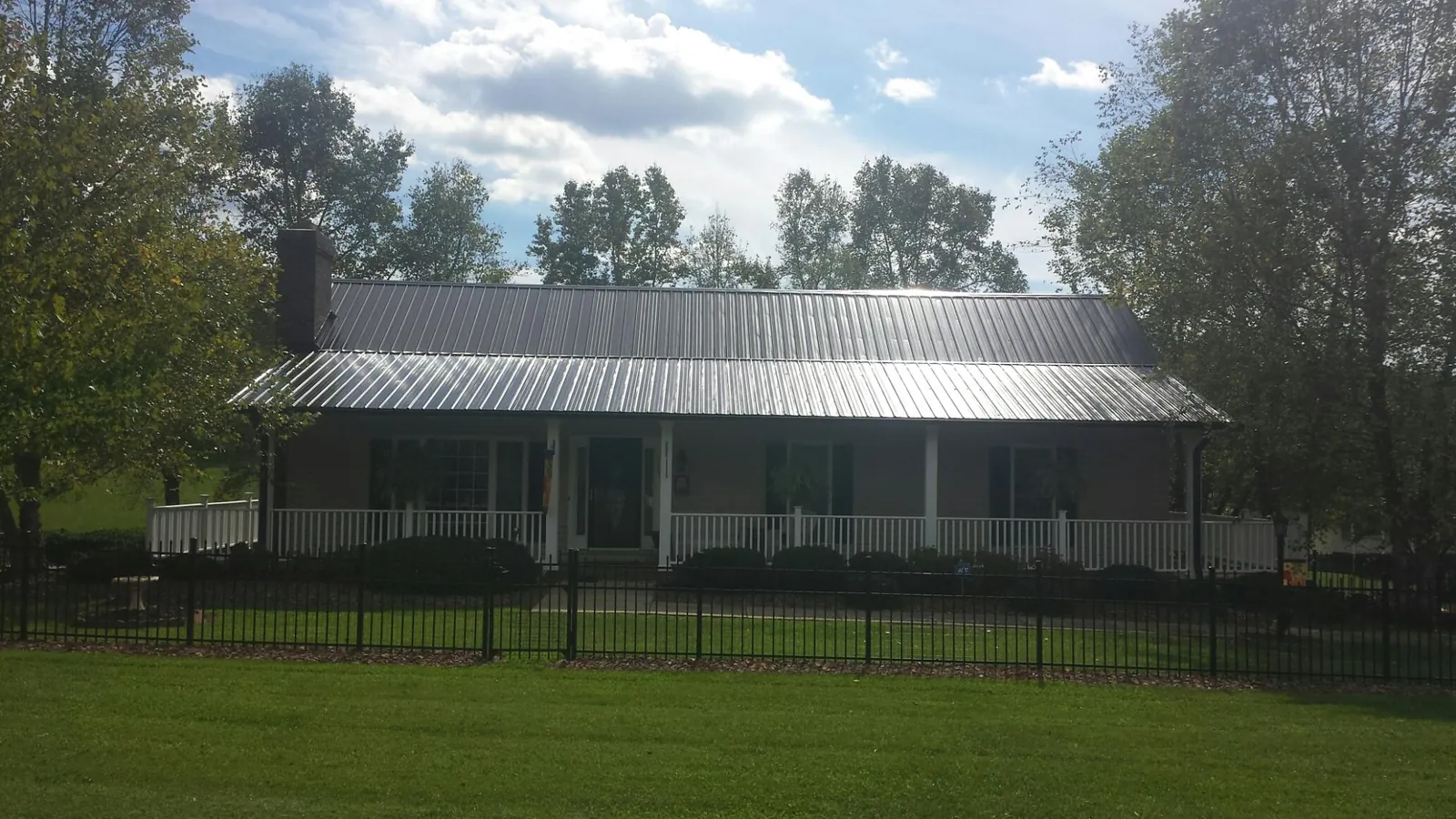 Gray metal roof on a brick ranch with a full width front porch — Gutter Guard Installation work by our crew in Gray Court