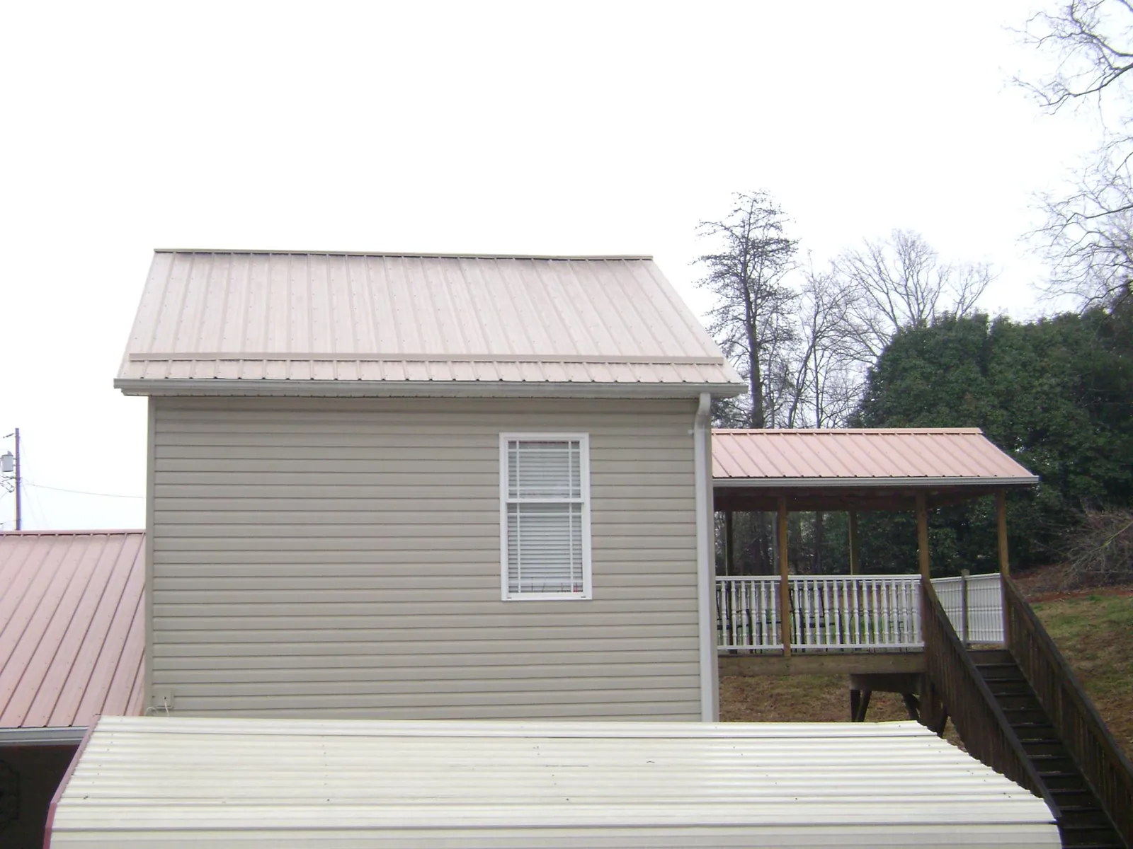 Tan metal roofs on a two story addition and attached porch, from a Roof Replacement job in Gray Court